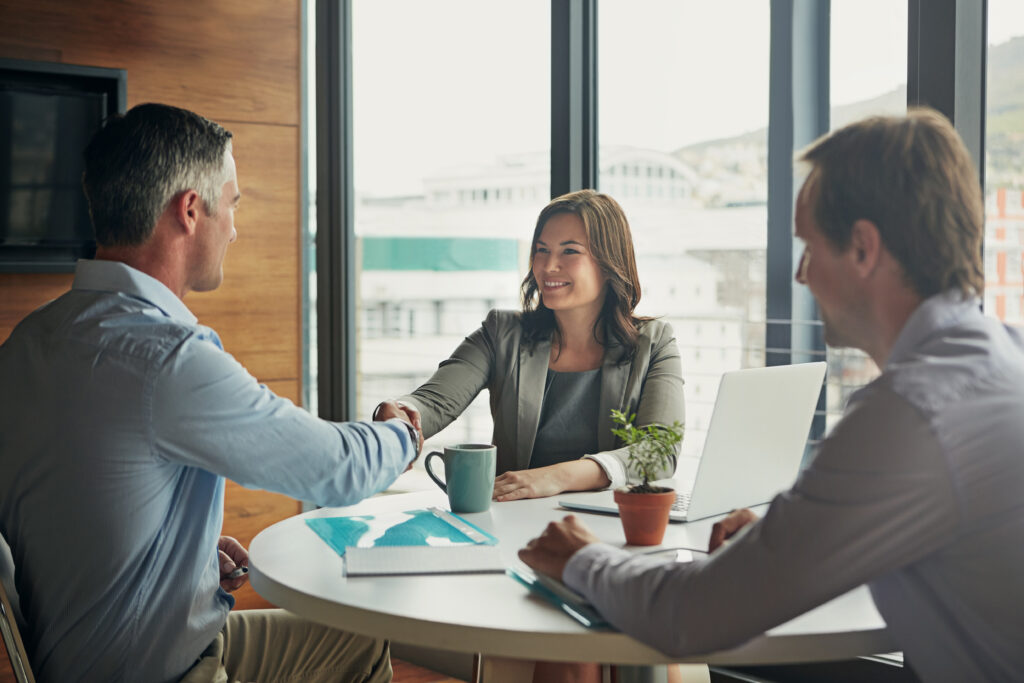 Business people, handshake and meeting or interview for b2b deal, teamwork or contract in corporate office. Men and a woman shaking hands for thank you, agreement and hiring or promotion as partner